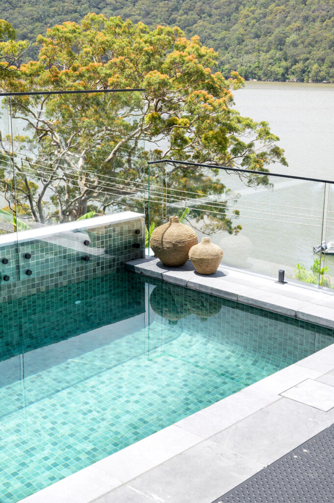 Infinity pool with glass fencing and waterfront views